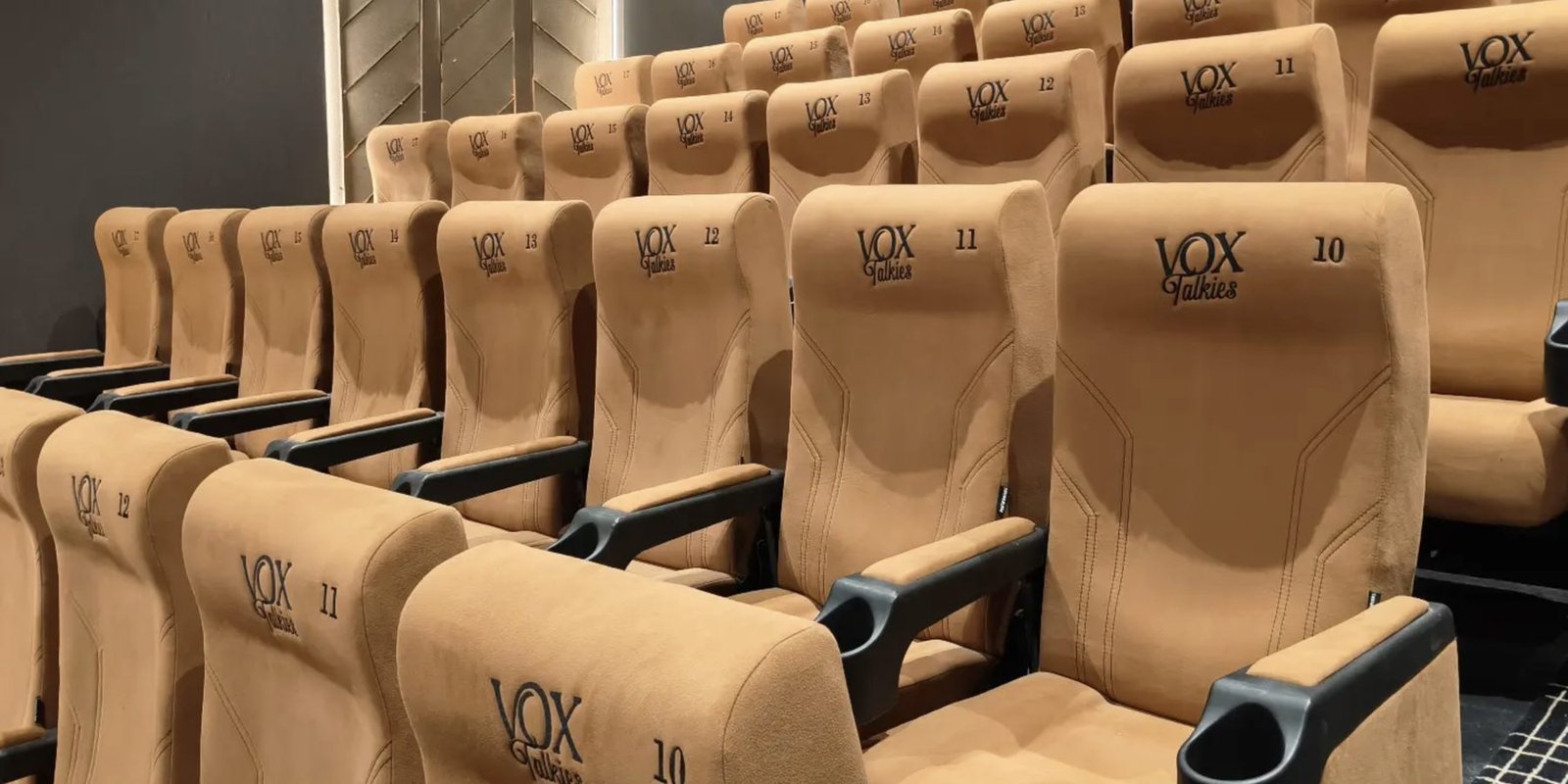 Rows of tan recliner seating angled toward the screen inside a Vox Talkies auditorium